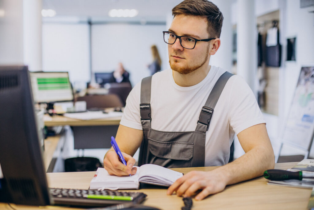 electrician writing down notes while looking on the computer